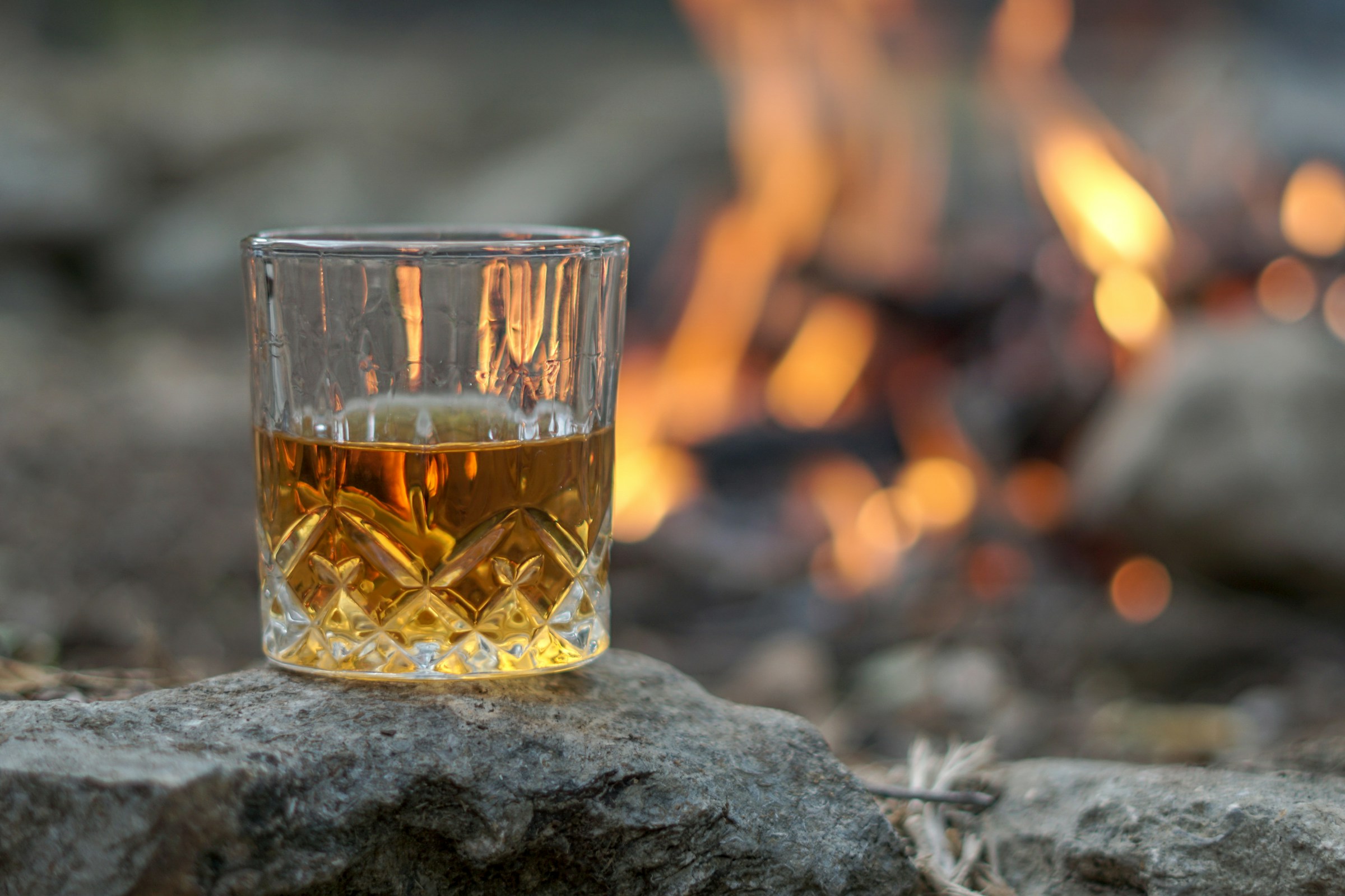 A glass of whisky catching amber light on a dark table