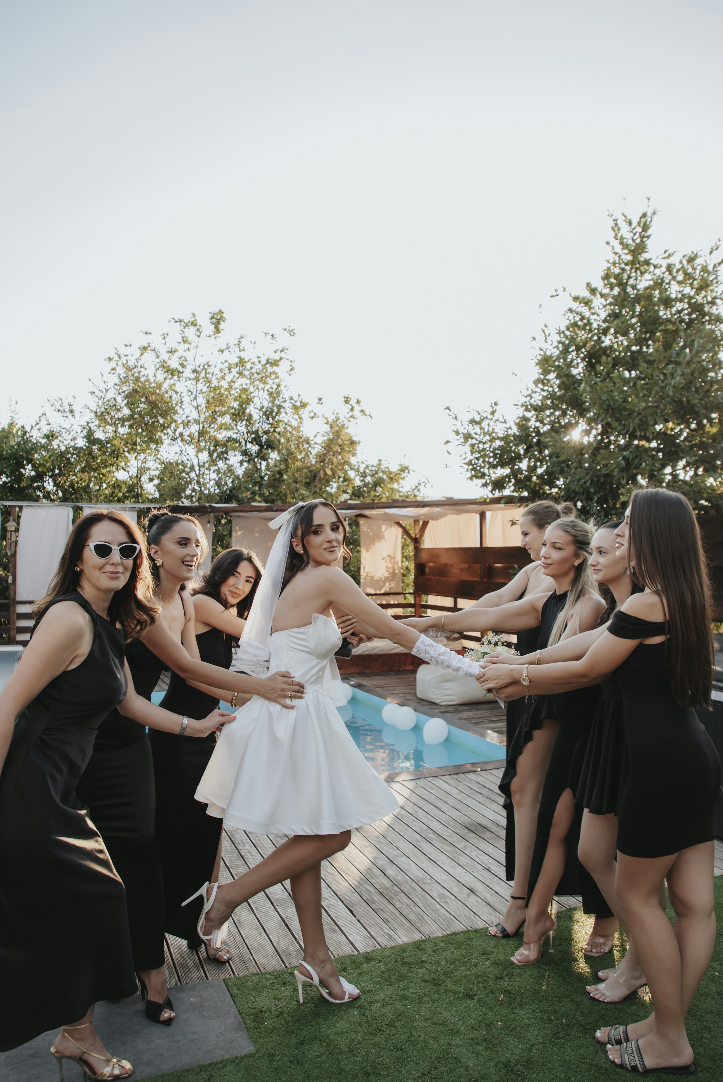 A bride and her bridesmaids holding hands outdoors